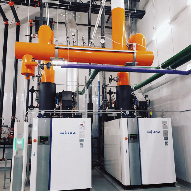 A white, industrial Miura steam boiler unit with a prominent control panel and mechanical components on a white background.