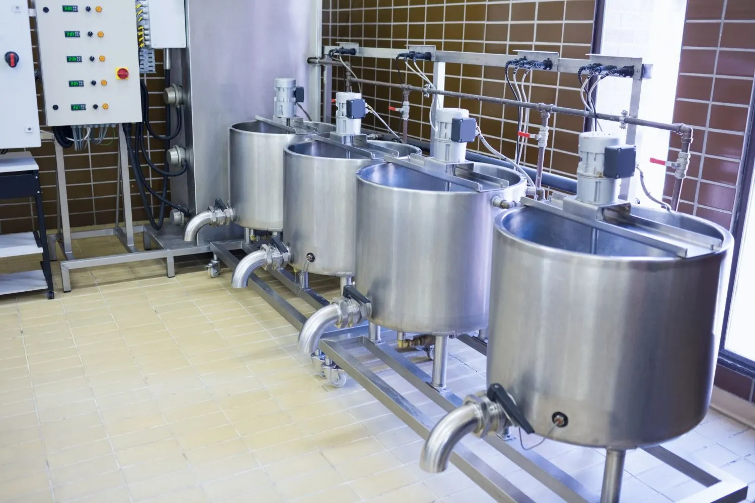 A row of stainless steel tanks from Boiler Technologies Unlimited is lined up in a room.
